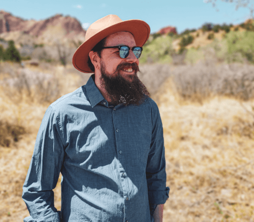 Bearded white guy wearing glasses and a wide-brim hat.